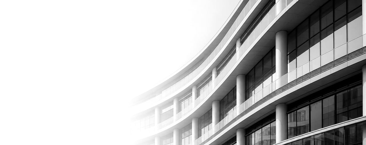 A sweeping monochrome view of a multi-story modern office building with curved balconies and tall columns, photographed in soft daylight.