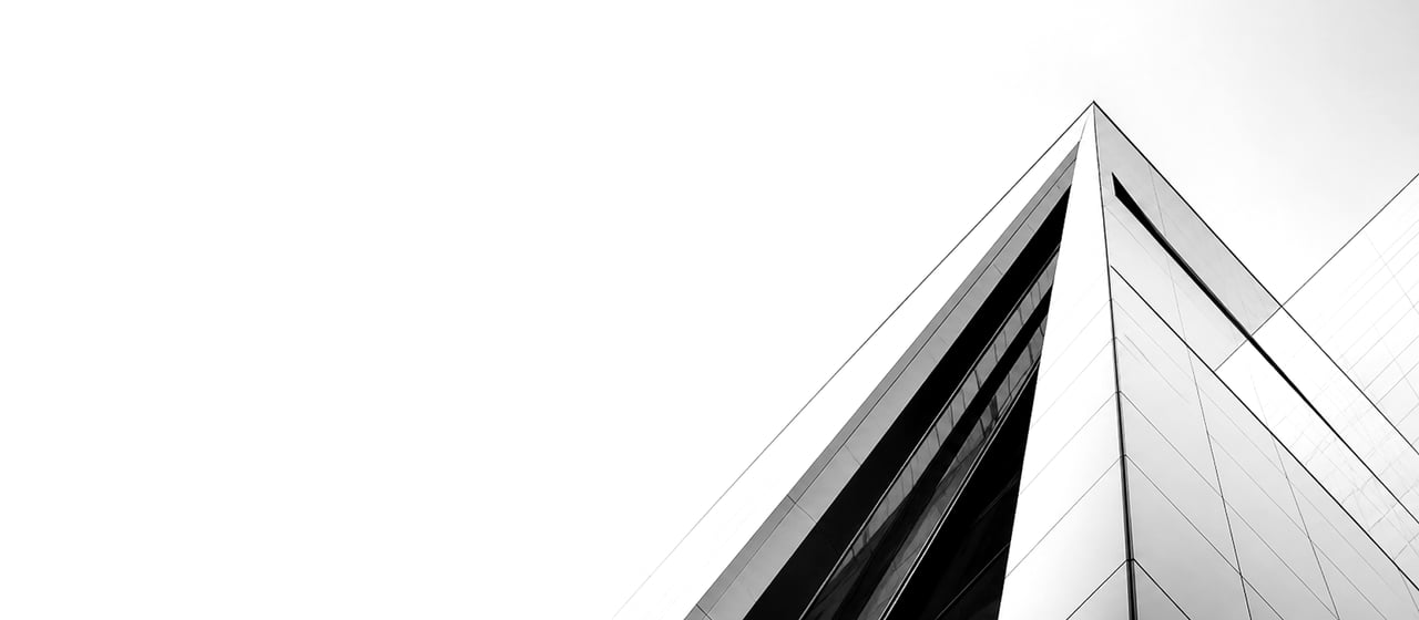 A pyramidal glass-and-steel skyscraper photographed against a near-white sky, its sharp edges catching the light.