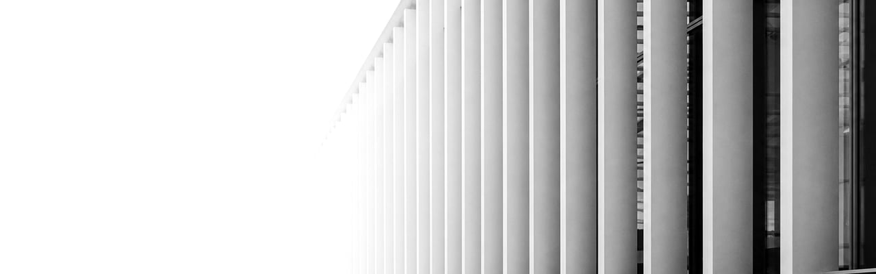 A precisely engineered modern building with repeating vertical structural columns receding into soft daylight.